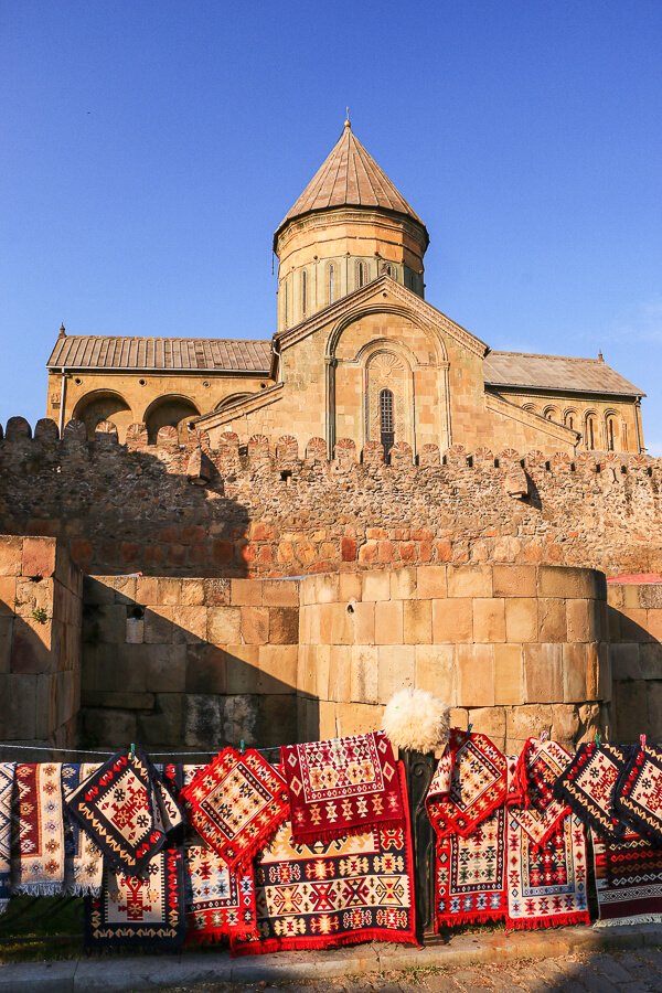 vendeurs de tapis orientaux dans Mtskheta et la cathédrale derrière